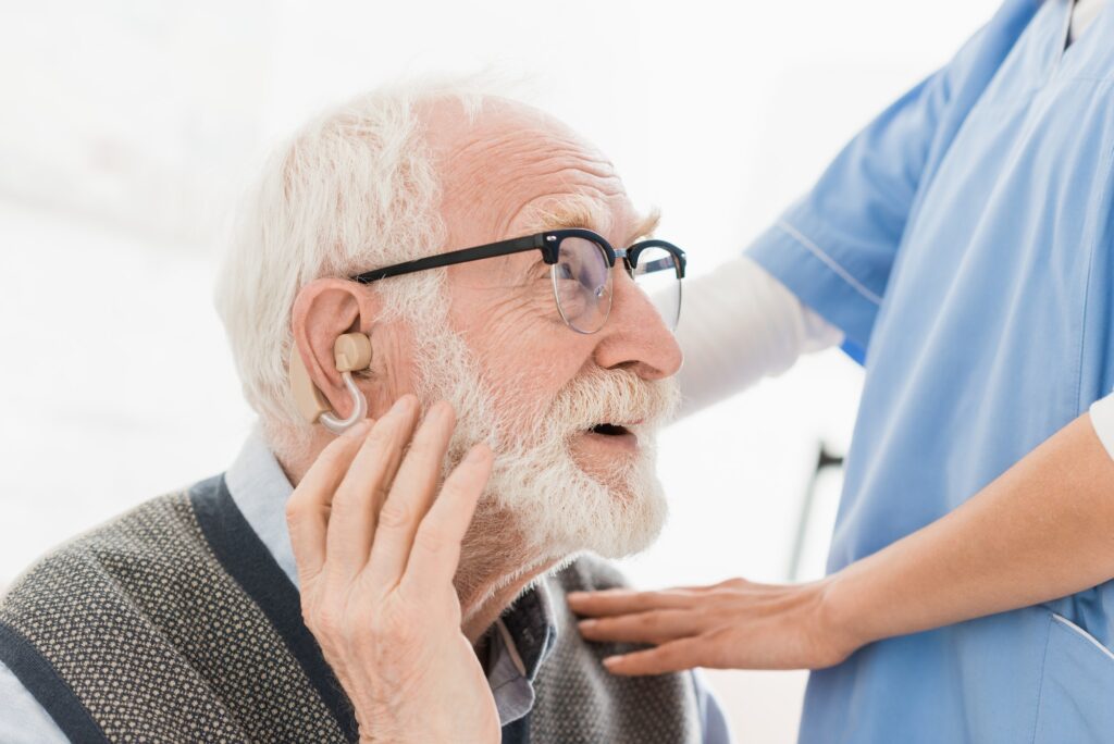 Profile of happy bearded man with hearing aid, looking away